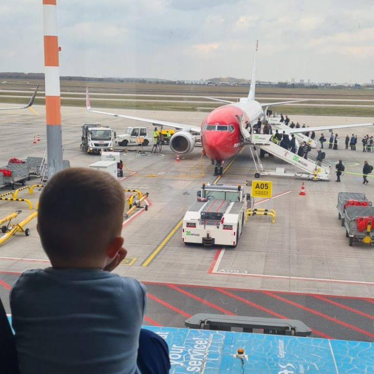 Kind am Flughafen schaut auf Flugzeuge – Symbol für Wohin auswandern mit Familie