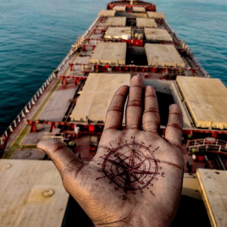Hand mit Kompass über einem Boot – Symbol für die Orientierung auf dem Weg ins passende Auswanderungsland